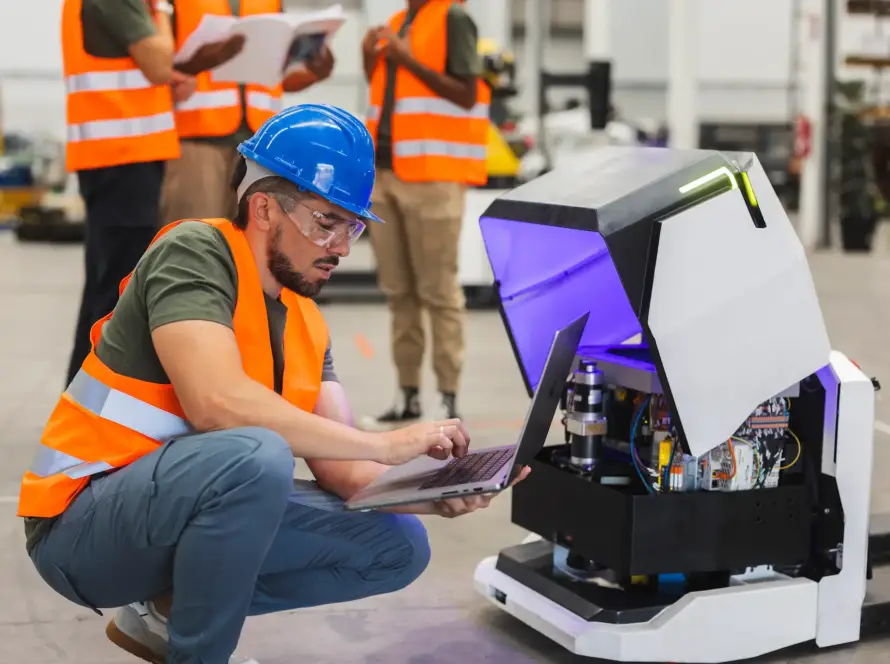 Ingeniero programando robot móvil autónomo durante la implementación en planta