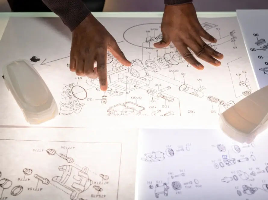 Ingeniero analizando planos técnicos de un prototipo automotriz sobre mesa de luz