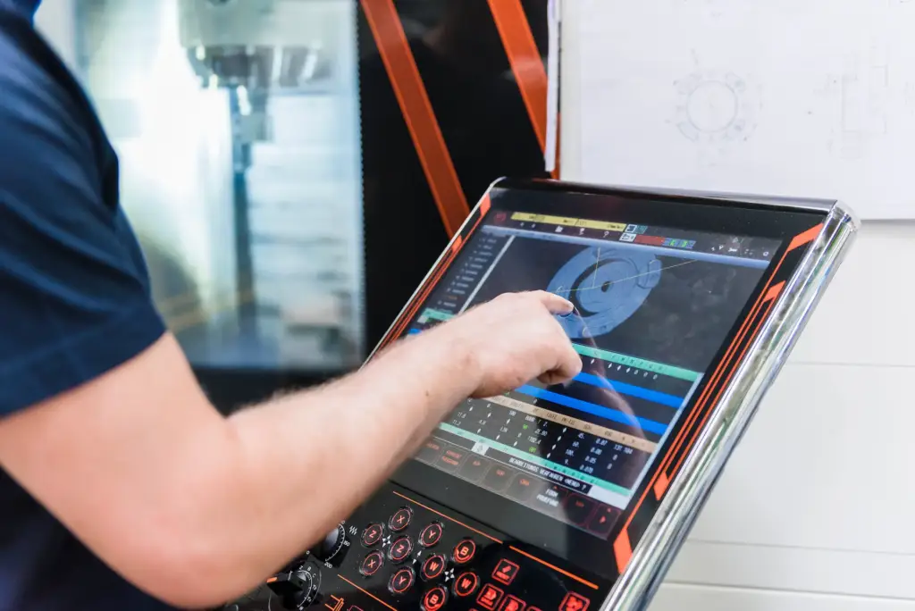 Operario ajustando parámetros en pantalla HMI de máquina CNC